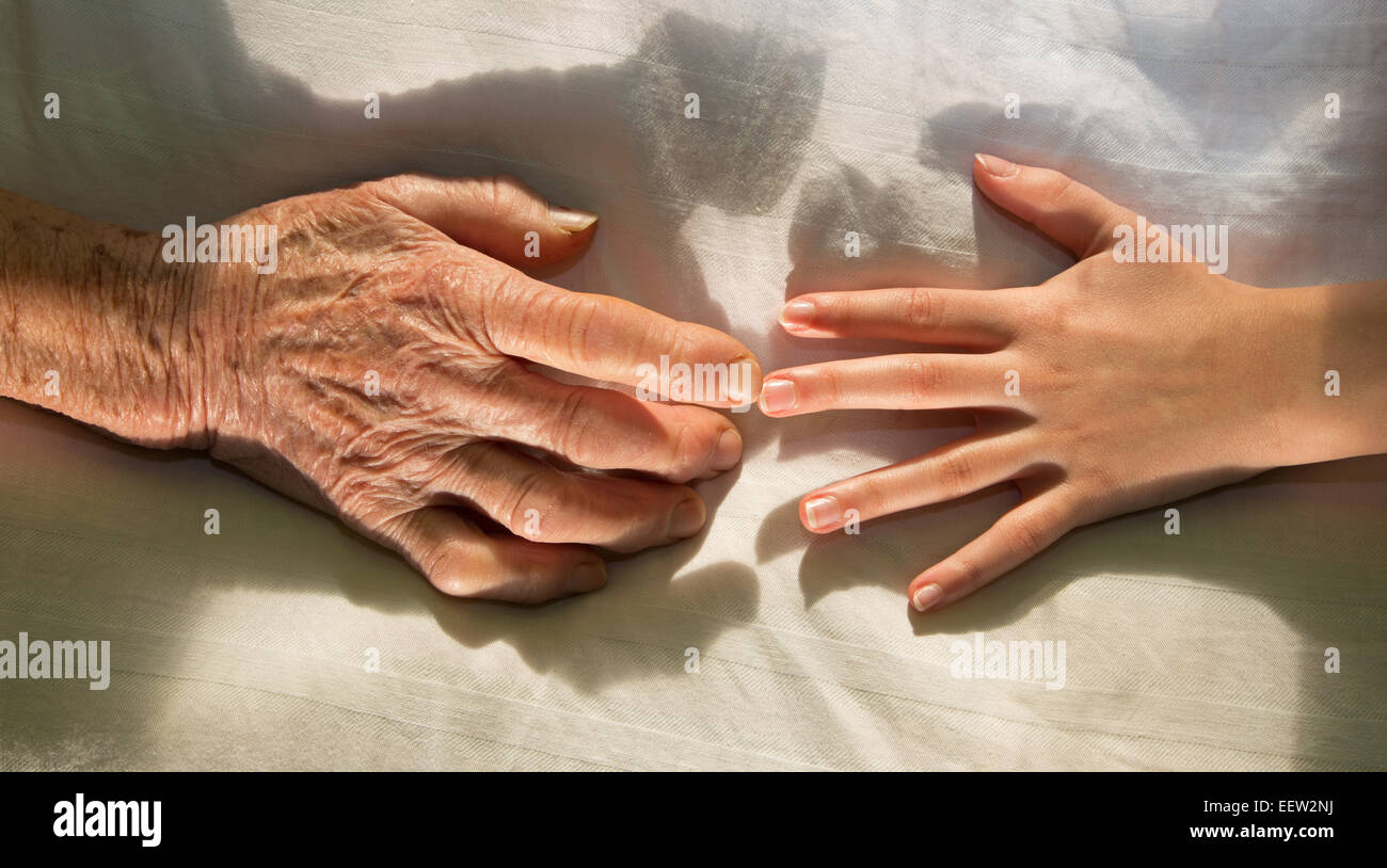 Mains de grand-mère et petit-fils dans le lit Banque D'Images