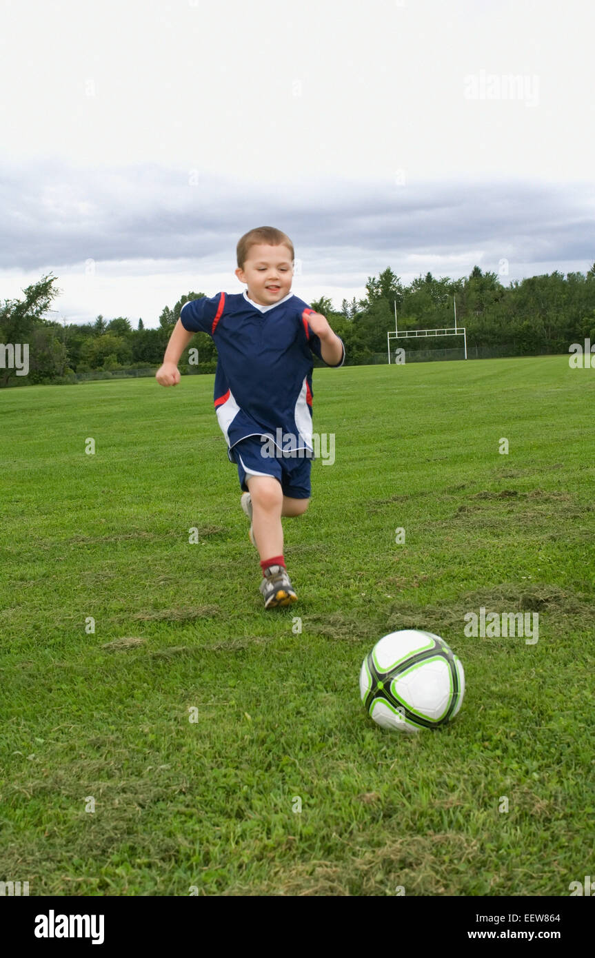 Jeune garçon jouant au football Banque D'Images