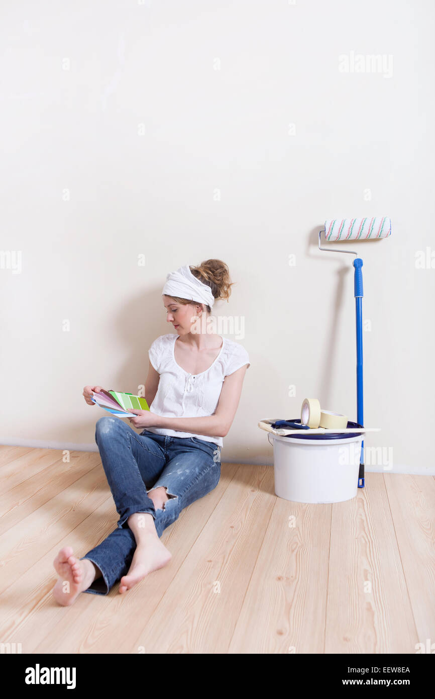 Une jeune femme veut peindre sa maison à la recherche d'une couleur appropriée Banque D'Images