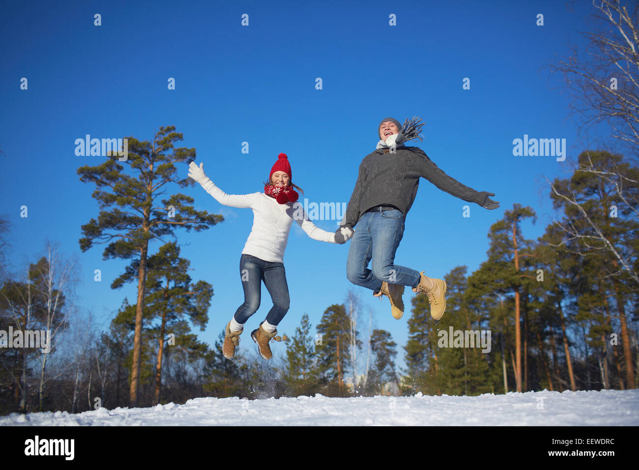 Jeune couple joyeux sautant en hiver parc ou la forêt Banque D'Images