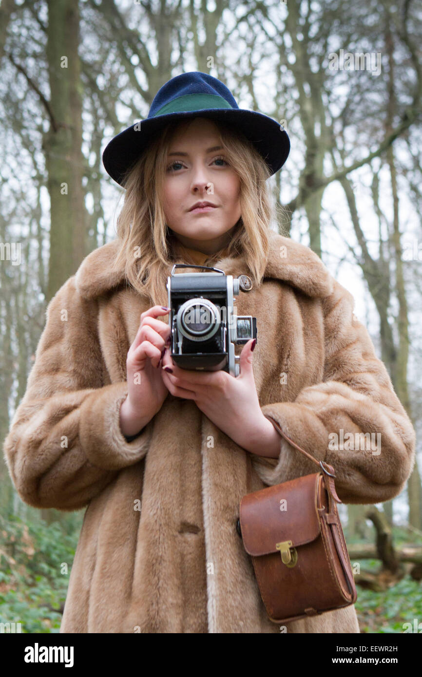 Une jeune femme avec un ancien rouleau appareil photo prend une photo dans un bois UK Banque D'Images