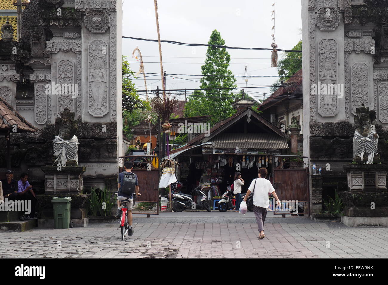 Cycliste et la femme dans le parking du musée d'Ubud, Bali. Banque D'Images