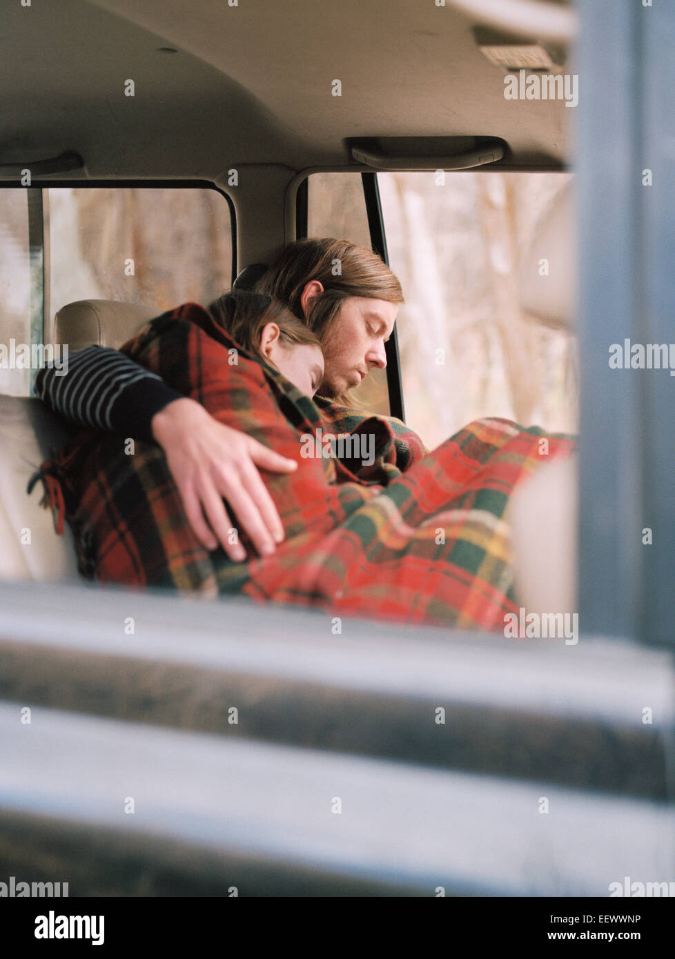 Un couple de prendre une sieste dans leur voiture, recouvert d'une couverture. Banque D'Images