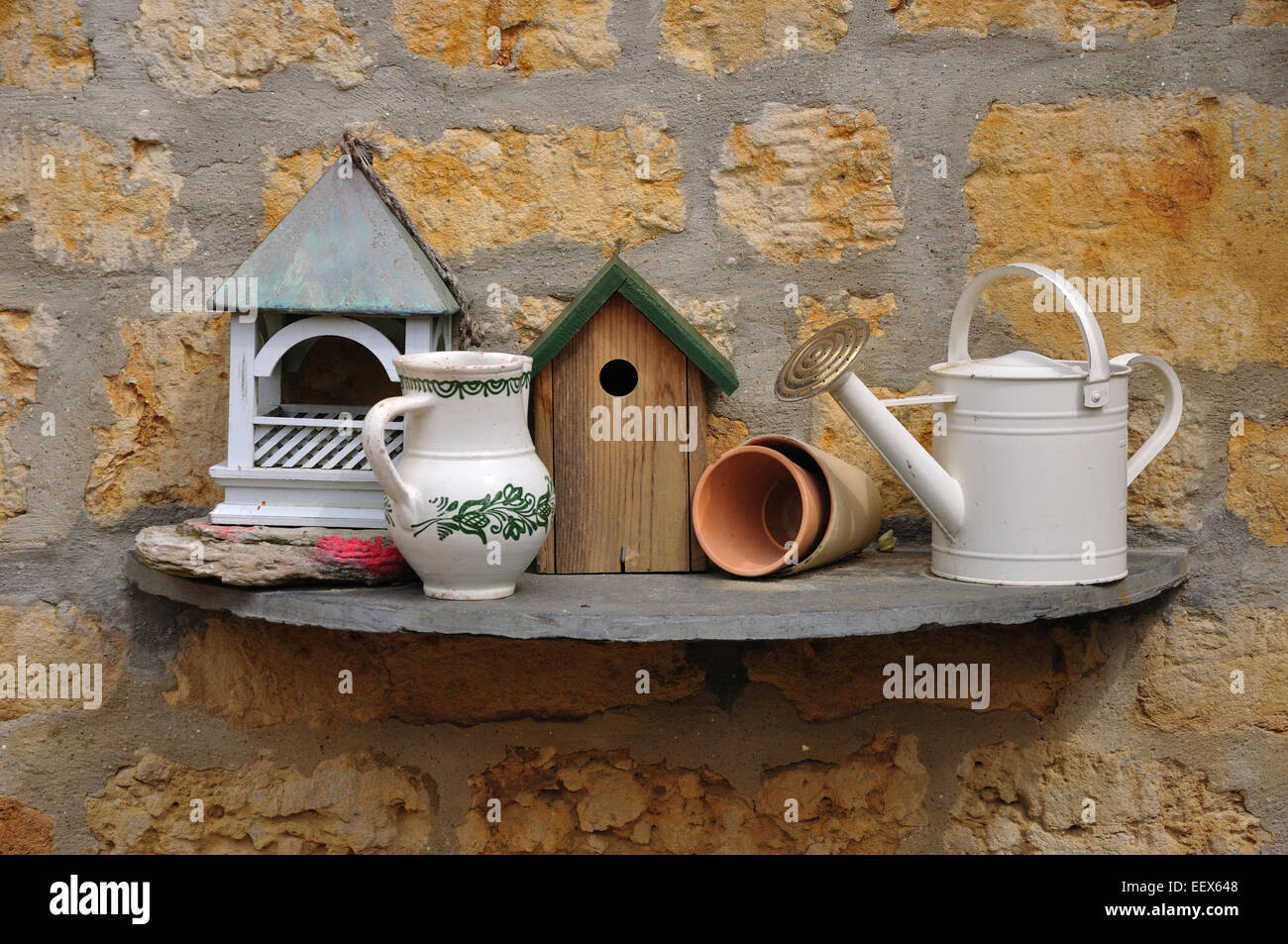 Un jardin avec nichoir, arrosoir, pots et verseuse UK Banque D'Images