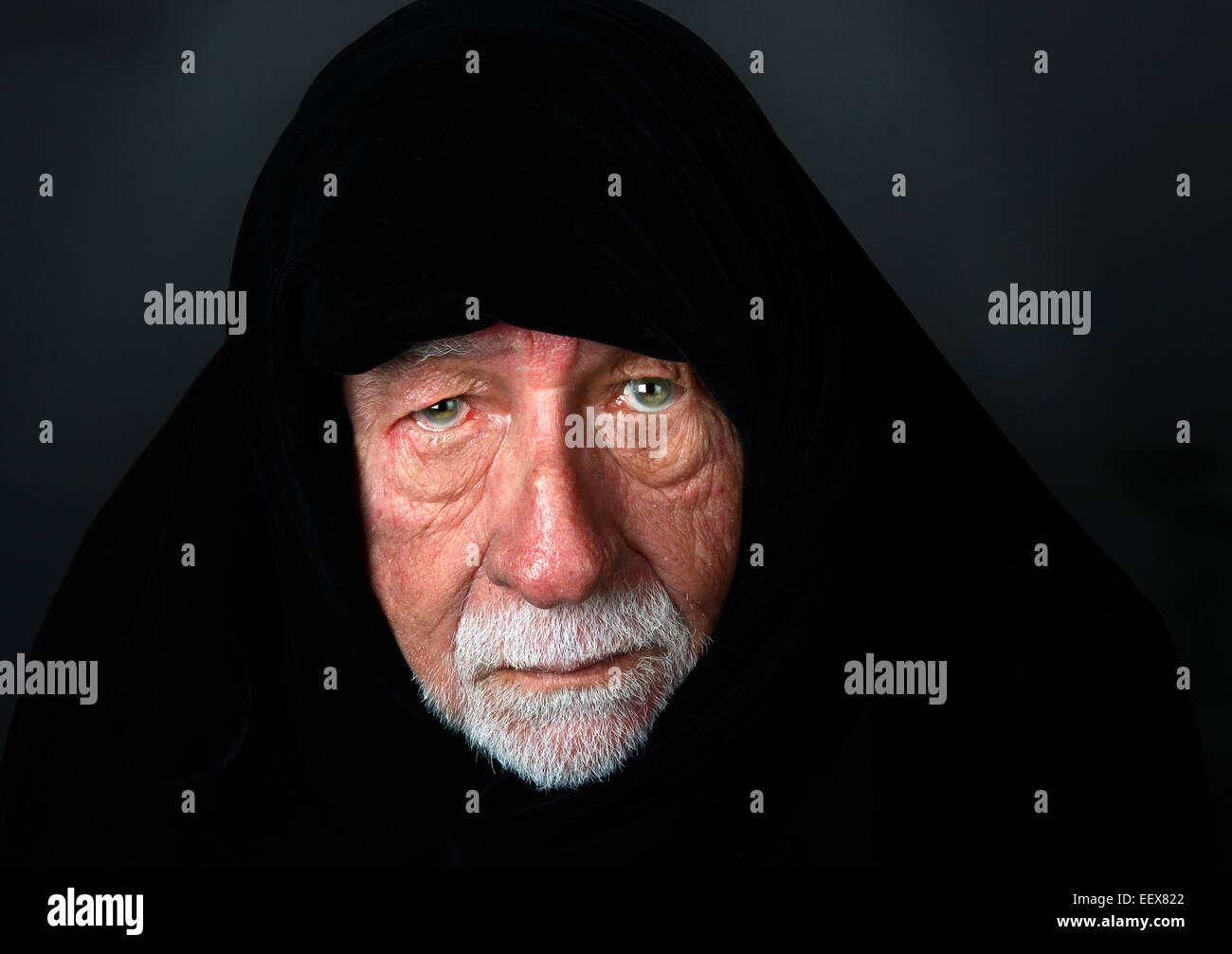 Sheik arabe aîné avec une expression sombre avec une coiffe noire à la recherche directement dans l'appareil photo Banque D'Images
