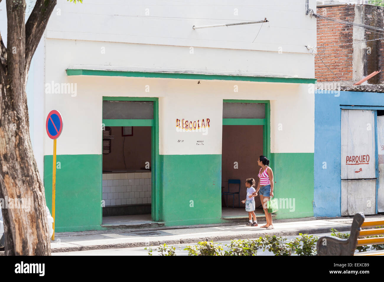 Style de vie cubain : une femme et sa fille à l'extérieur d'une boutique 'El escolar" (l'élève) à Camaguey, Cuba, troisième ville Banque D'Images