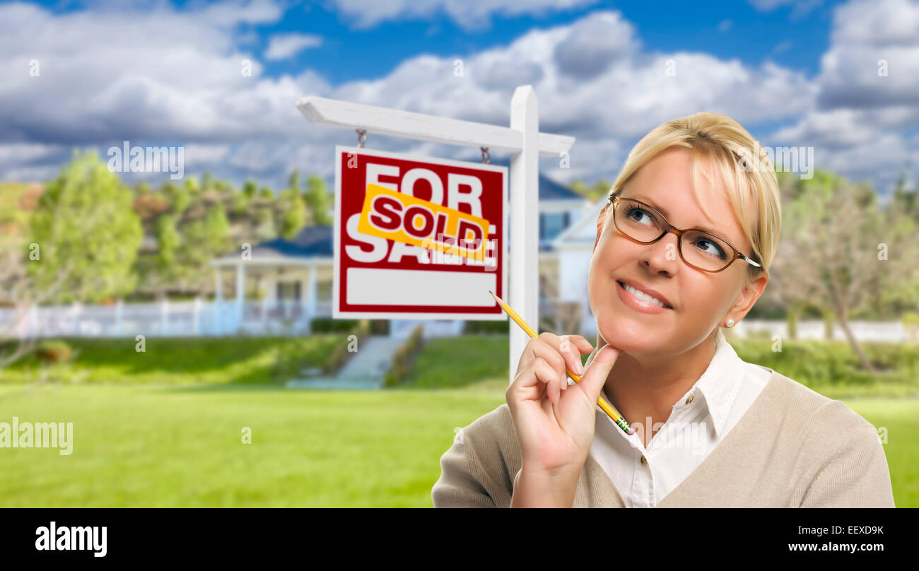 Young Adult Woman avec crayon en face de vendus Achat Immobilier signe et maison. Banque D'Images