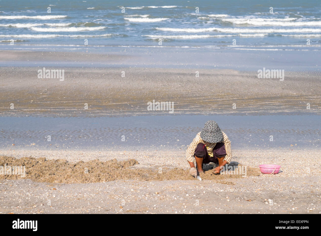 La vie est une plage - Thai Woman picking moules à la plage de Baie des Dauphins, Prachuap Khiri Khan, Thaïlande. Banque D'Images