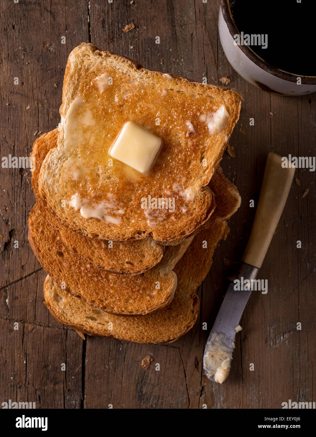Tranches de pain croûté beurrée sur une table rustique avec du café. Banque D'Images