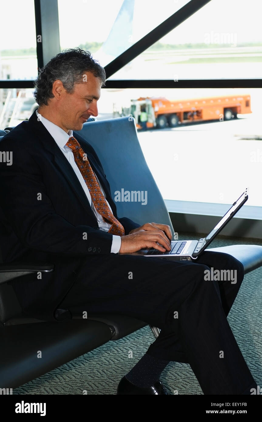 Businessman in airport using laptop Banque D'Images