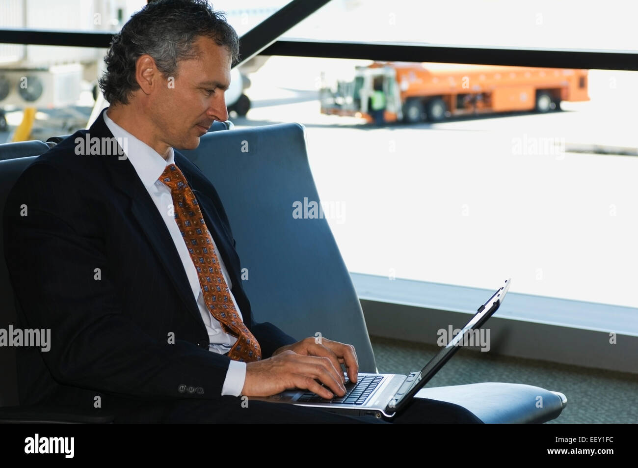 Businessman in airport using laptop Banque D'Images