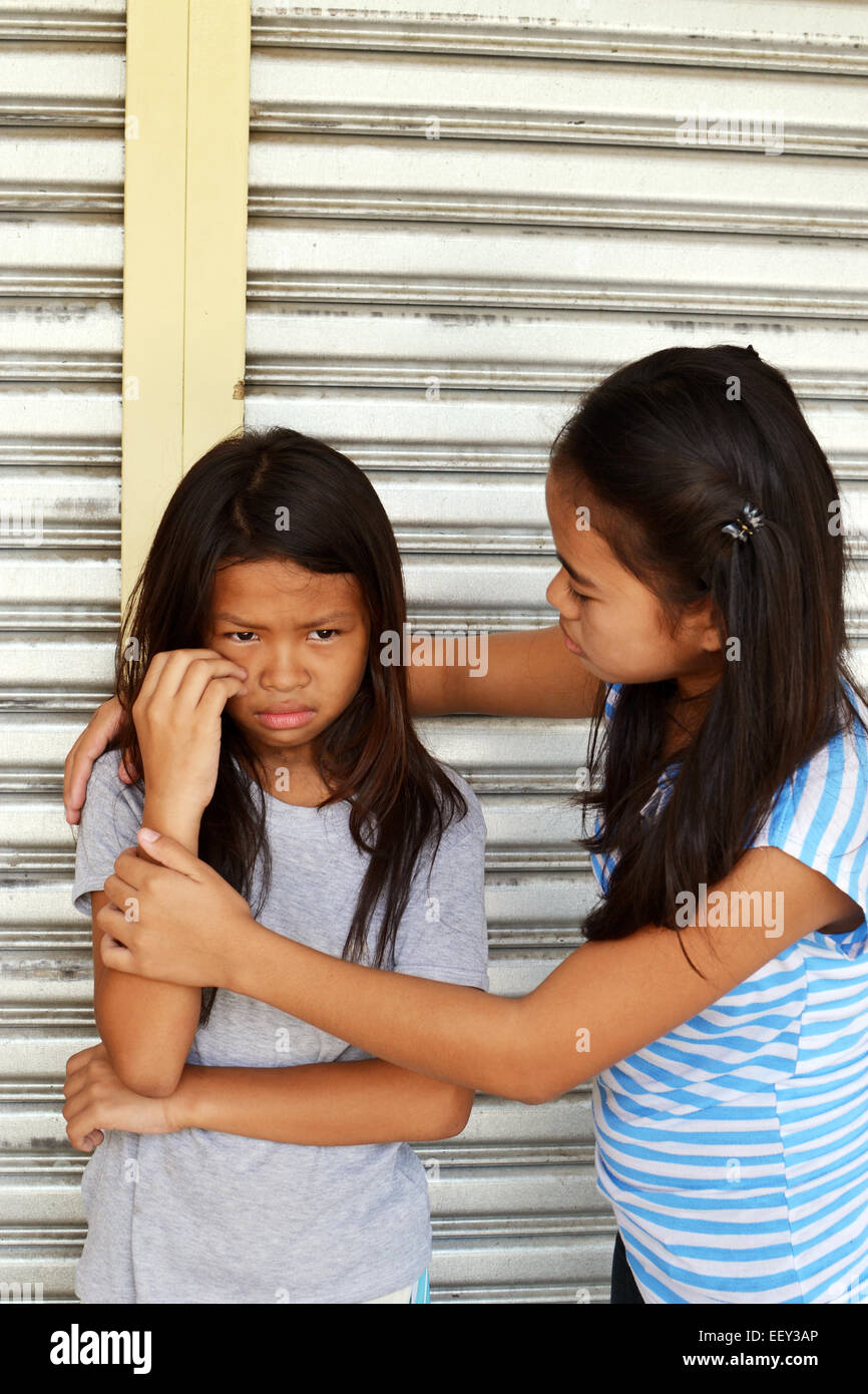 Une jeune femme sans-abri réconfortant un pauvre enfant pleurer dans la rue Banque D'Images