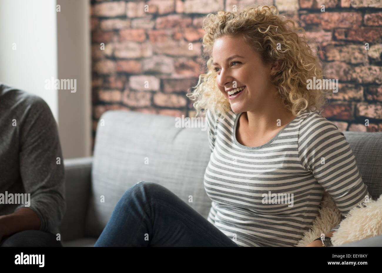 Blonde woman laughing on sofa Banque D'Images