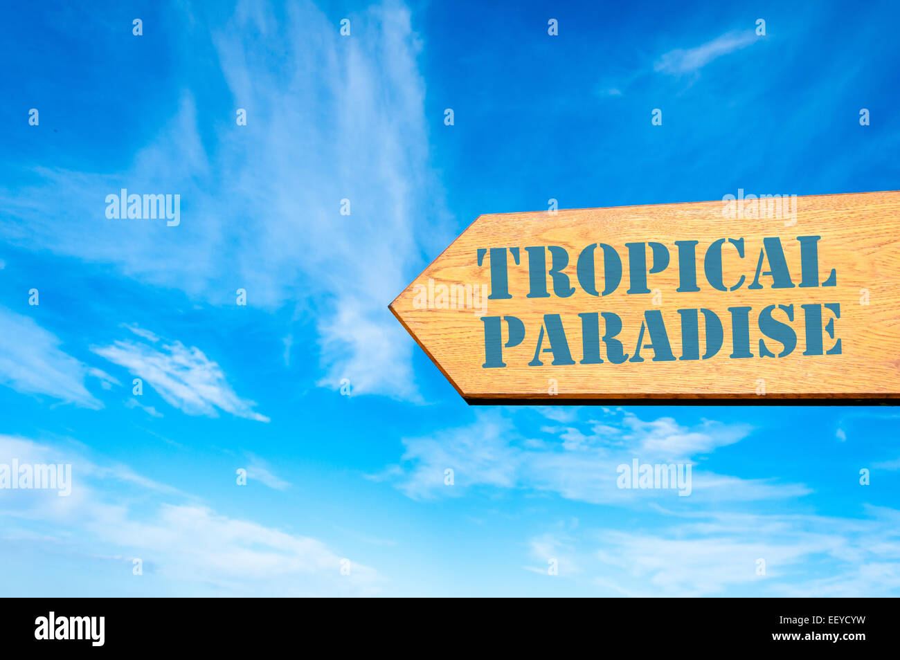 Bois panneau de flèche contre ciel bleu avec message paradis tropical, Vacances Banque D'Images