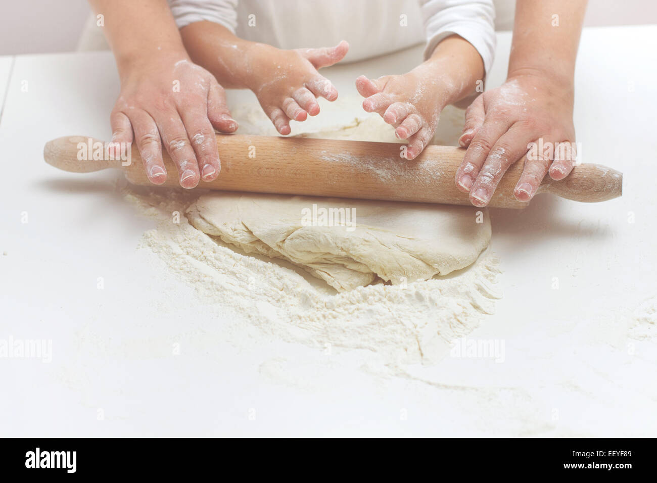 Mère et fille mains pétrissant la pâte sur la table. Banque D'Images