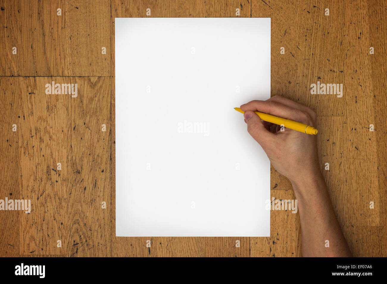 Hand holding pen sur une feuille de papier blanc sur une surface de table en bois usé, vu du dessus Banque D'Images