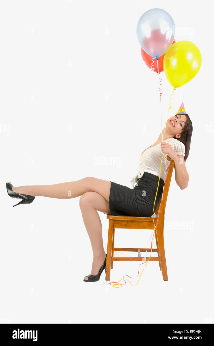 Woman wearing party hat and holding balloons Banque D'Images