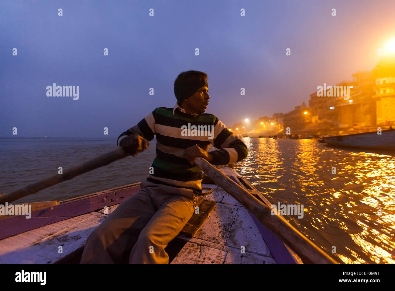 VARANASI, INDE - 05 janvier, 2015 : un homme l'aviron en bois d'un bateau de tourisme sur le Gange juste avant le lever du soleil. Banque D'Images