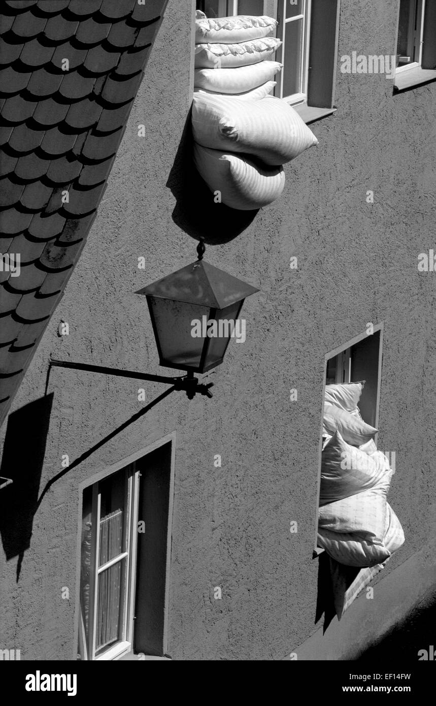 La literie et les oreillers sont farcies en deux fenêtres ouvertes pour l'air au cours de la matinée dans une maison moderne dans la ville médiévale de Rothenburg ob der Tauber dans la région de Bavière en Allemagne. La diffusion quotidienne de literie à l'extérieur dans l'air frais est une tradition de beaucoup d'Allemands, qui ont l'habitude de dormir sous une couette en duvet (Federbett). Le noir et blanc. Banque D'Images