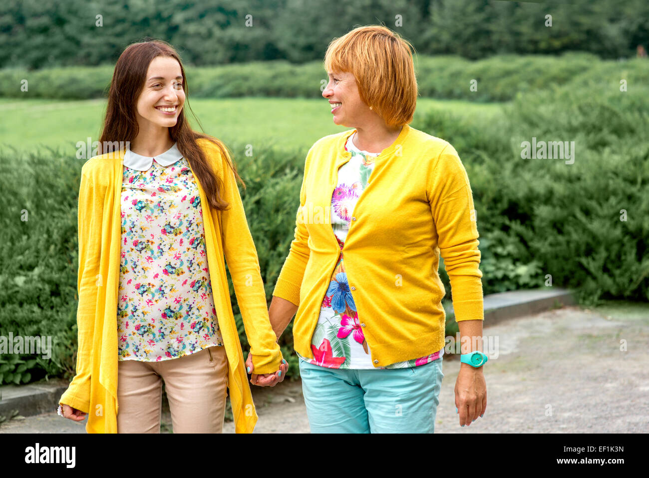 La marche de la mère avec sa fille habillé en jaune dans le parc Banque D'Images