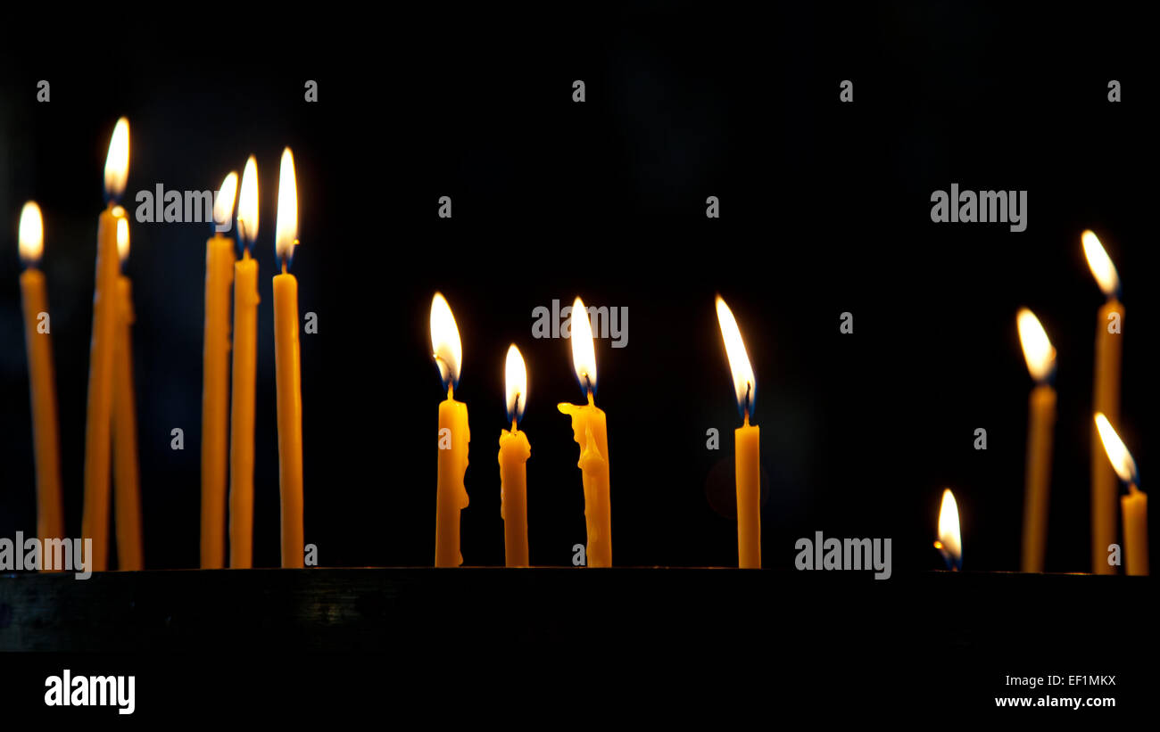 Plusieurs grandes bougies allumées dans une pièce sombre à l'église Banque D'Images