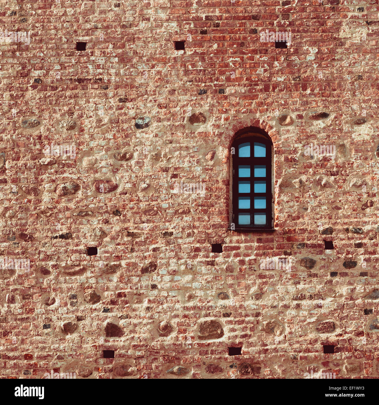 Petite fenêtre cintrée dans un mur de brique rouge Château Banque D'Images
