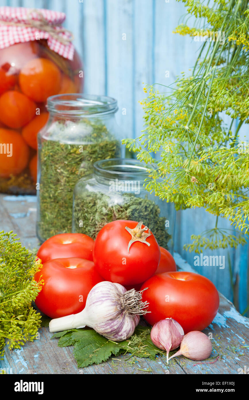 Des tomates en conserve dans un bocal en verre. Les légumes frais et les épices sur planche de bois Banque D'Images