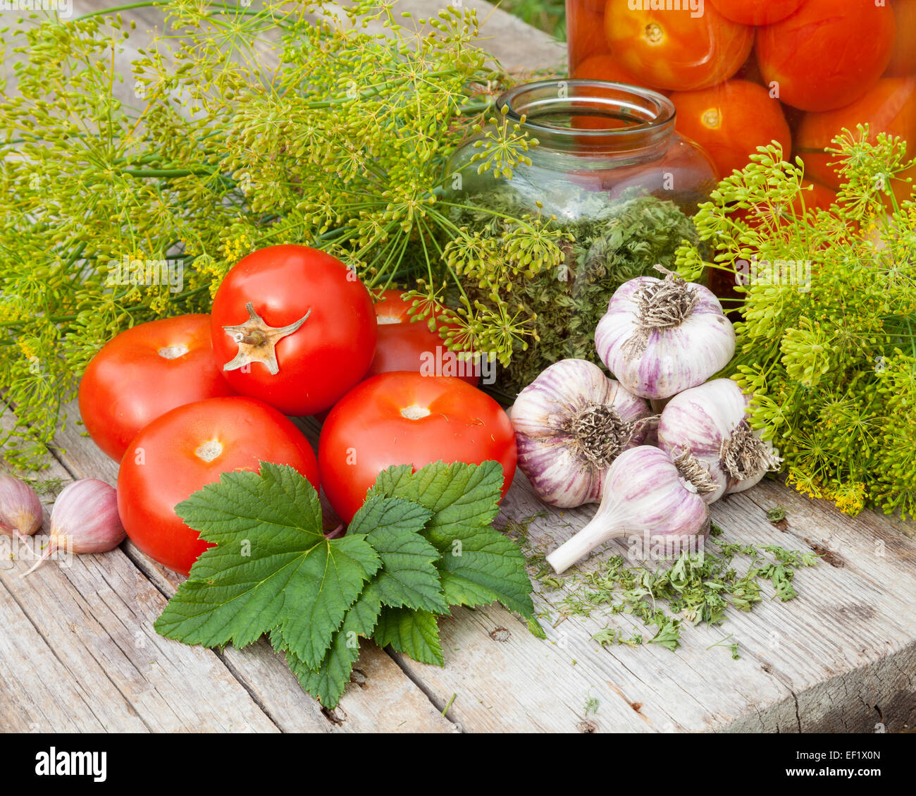 Légumes et épices sur planche de bois. Des tomates en conserve dans un bocal en verre. Banque D'Images