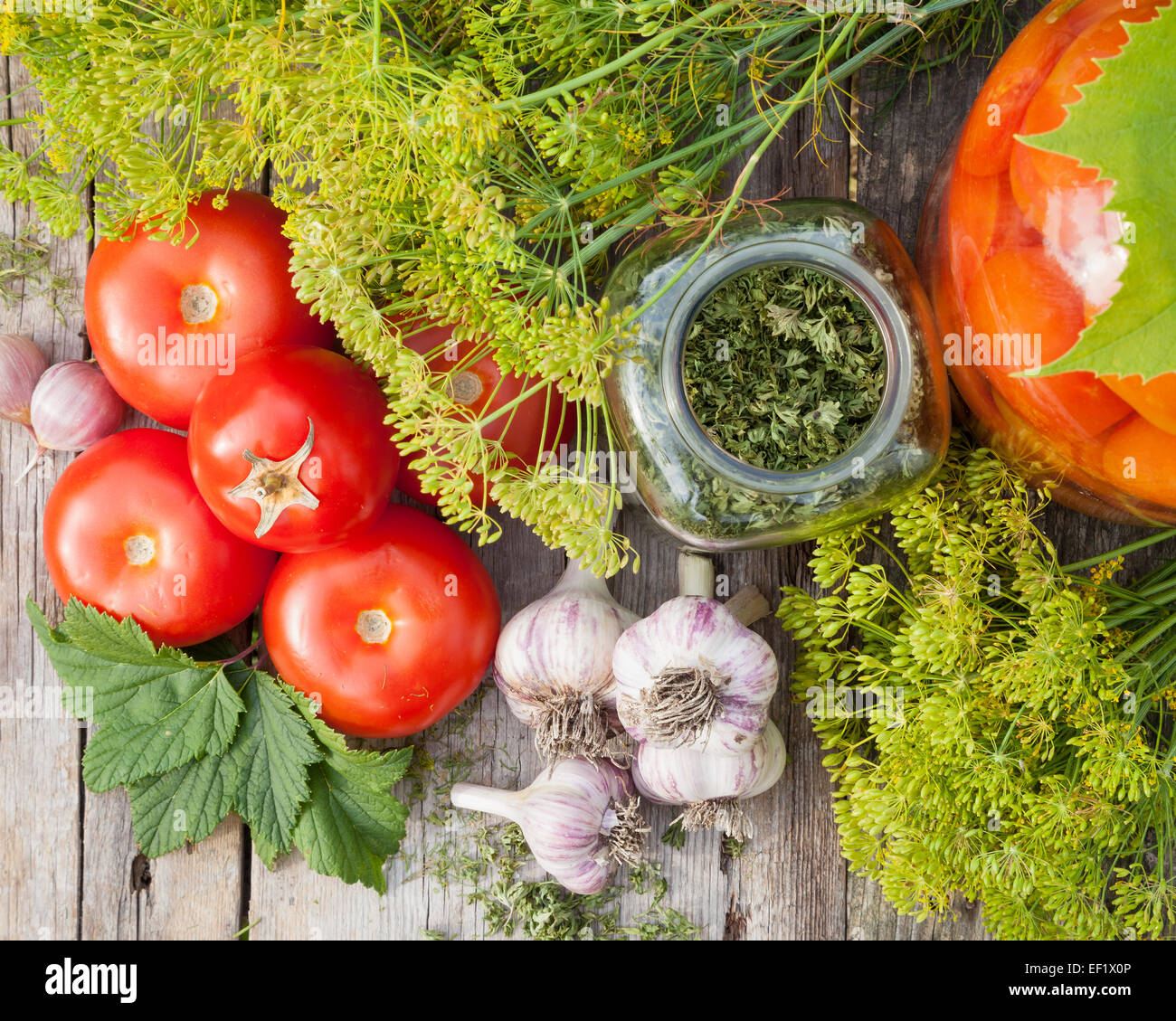 Des tomates en conserve dans un bocal en verre. Les légumes frais et les épices sur planche de bois, vue du dessus Banque D'Images