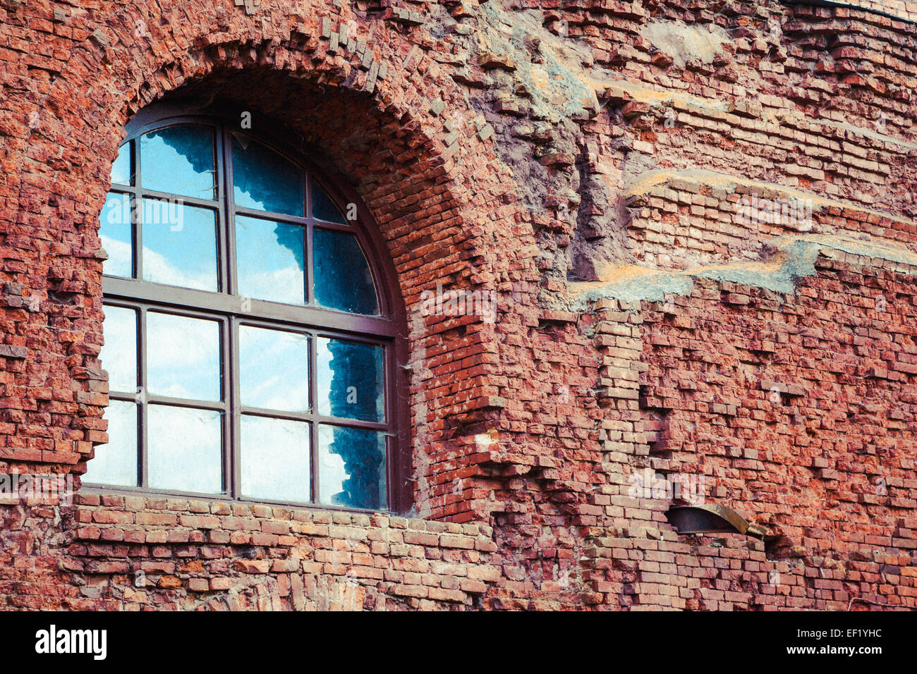 Fenêtre cintrée dans un mur de brique rouge Banque D'Images