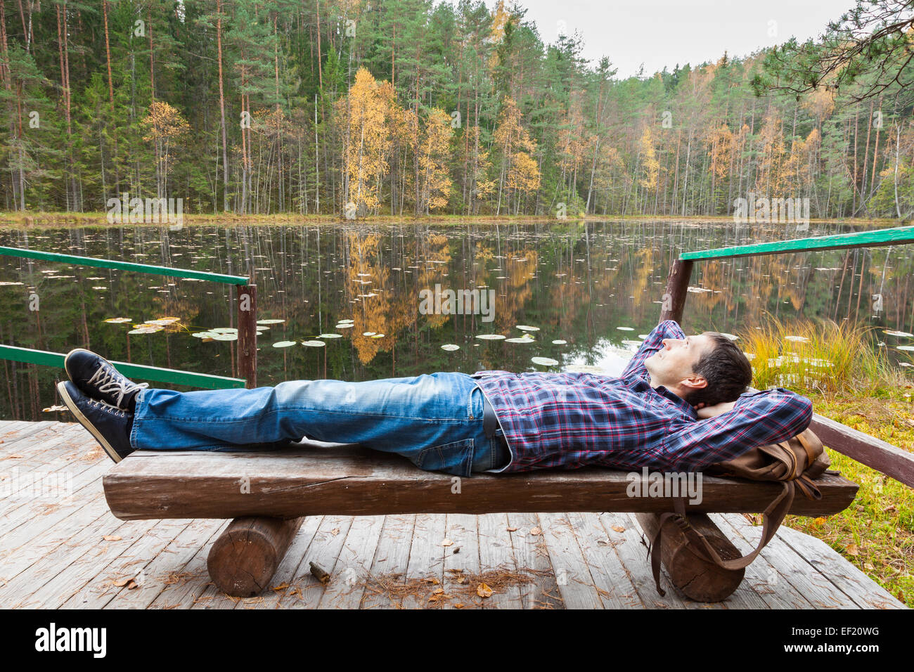 Young male hiker resting près du lac en forêt d'automne Banque D'Images