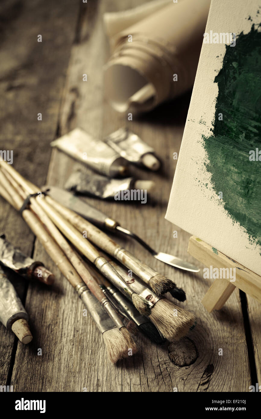 Pinceaux artistiques, tubes de peinture, couteau avec chevalet et peinture à l'huile sur le vieux bureau en bois. Vintage photo stylisée. Banque D'Images