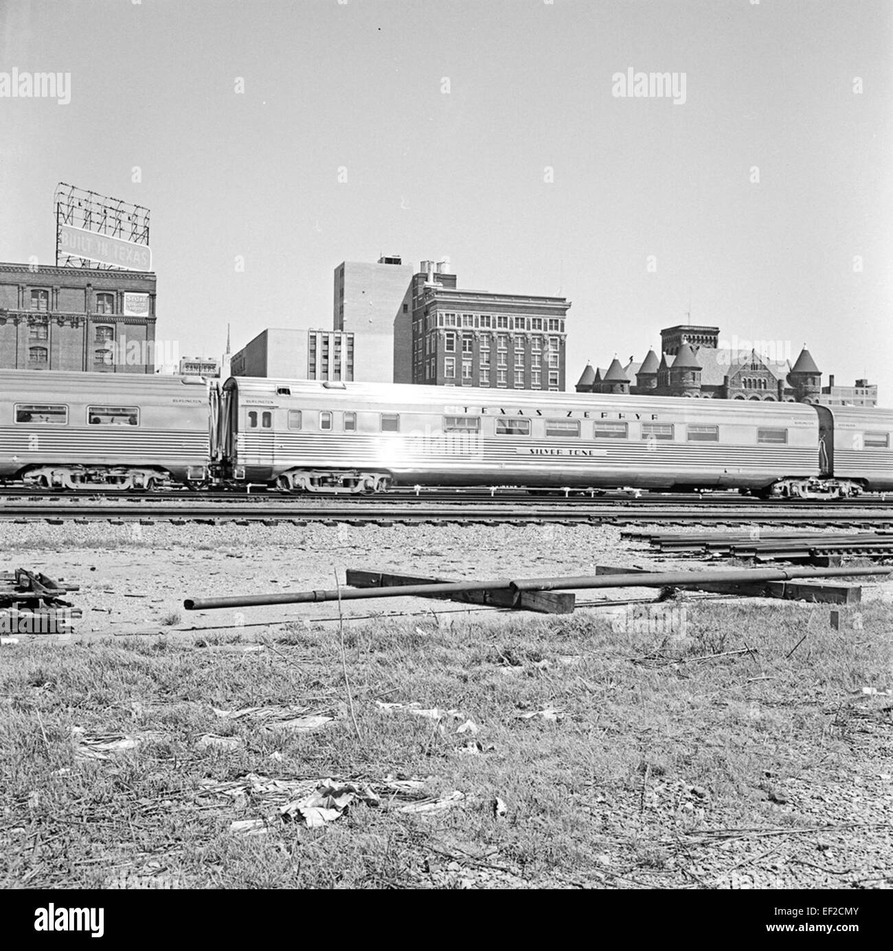 Le wagon-lit « Silver Tone » sur le Fort Worth & Denver City Railroad représente le voyage en train du début du XXe siècle, offrant un confort aux passagers pendant les longs trajets. L'image présente des monuments clés, dont l'Old Red Courthouse et le Texas School Book Depository, ainsi que d'importantes infrastructures ferroviaires. Banque D'Images