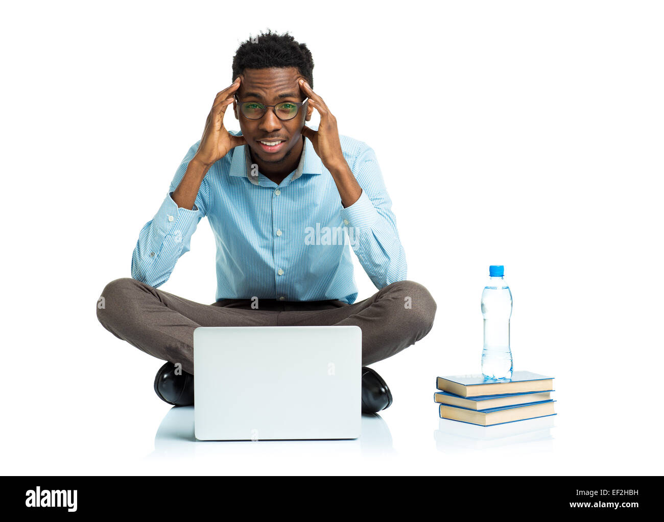 African American college student avec maux de tête assis sur fond blanc avec ordinateur portable et quelques livres Banque D'Images