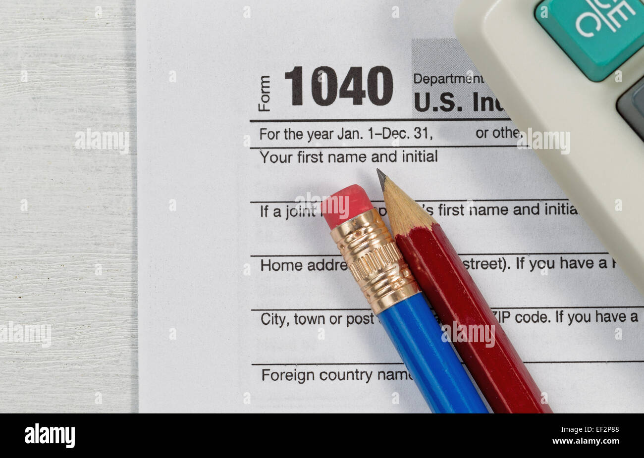 Close up U.S. l'impôt sur le formulaire 1040 avec une pension partielle et la calculatrice de bureau en bois sur les crayons. Se concentrer sur des crayons. Banque D'Images