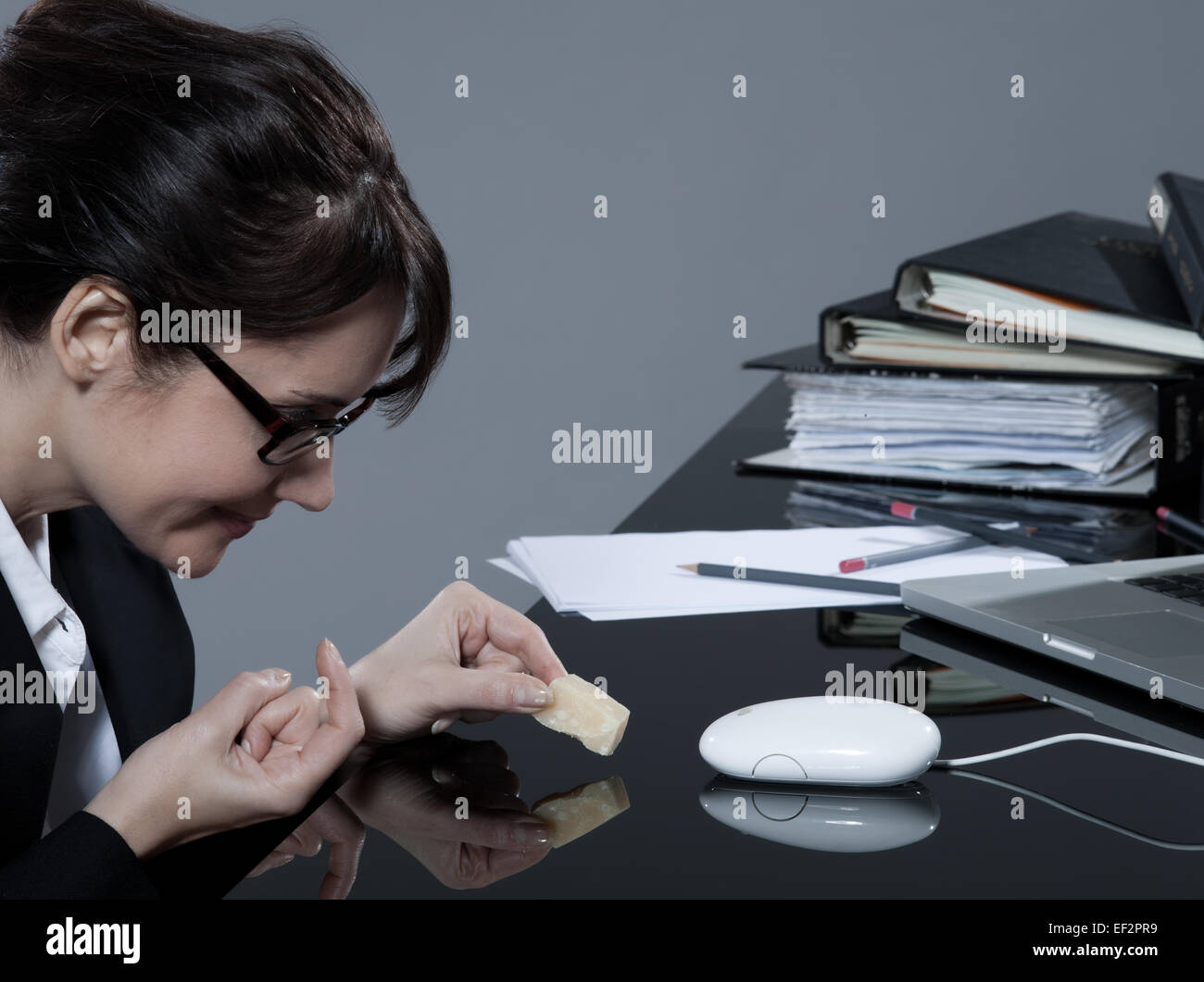 Belle brune femme d'affaires à son bureau d'essayer de piéger sa souris d'ordinateur avec du fromage Banque D'Images