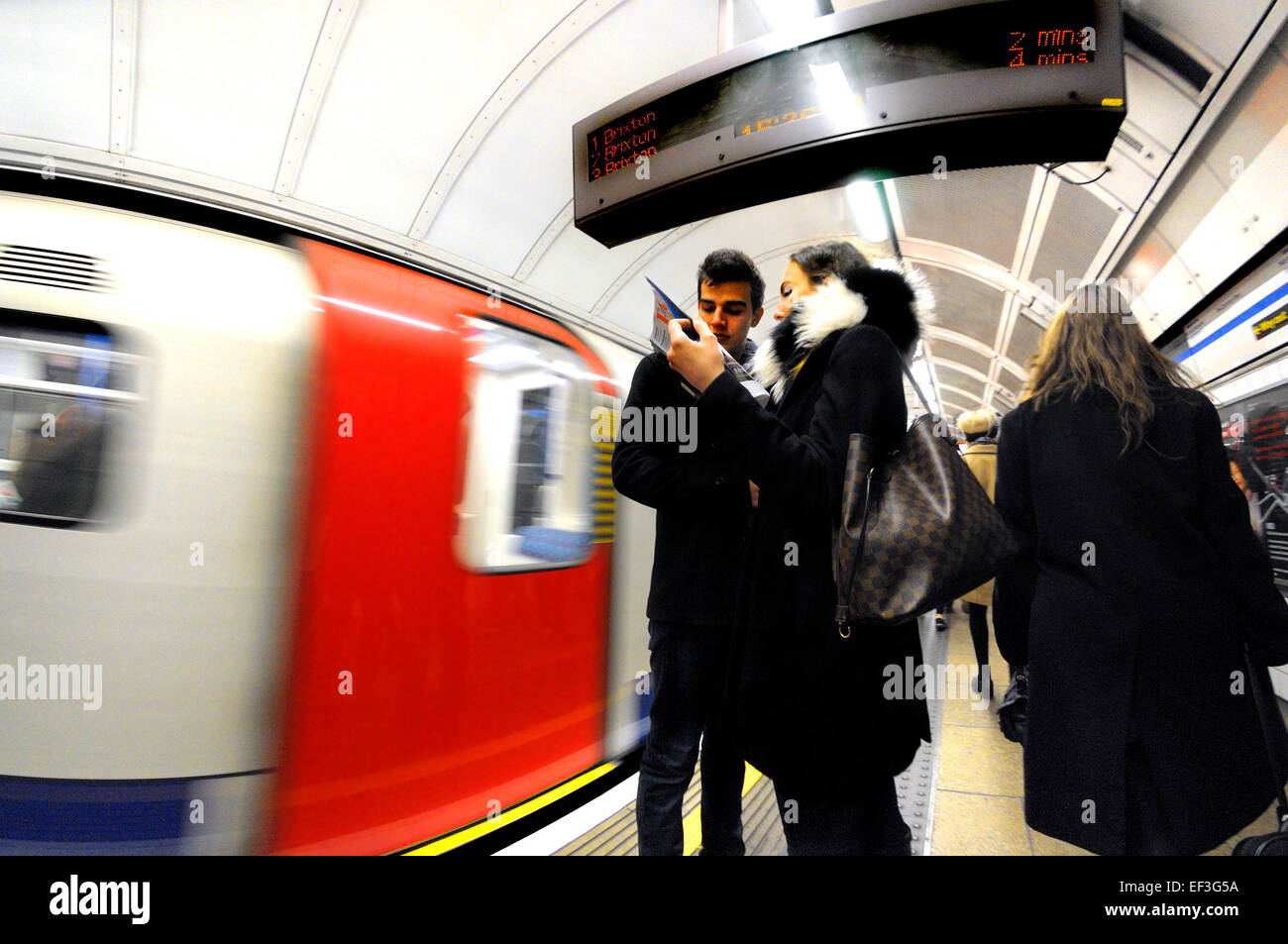 Londres, Angleterre, Royaume-Uni. Métro de Londres / le tube. Jeune couple à la recherche d'un magazine Banque D'Images