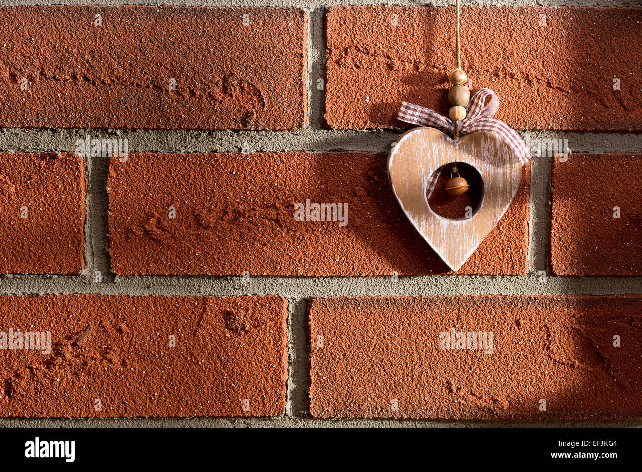 Le coeur en bois accroché sur un mur de briques Banque D'Images