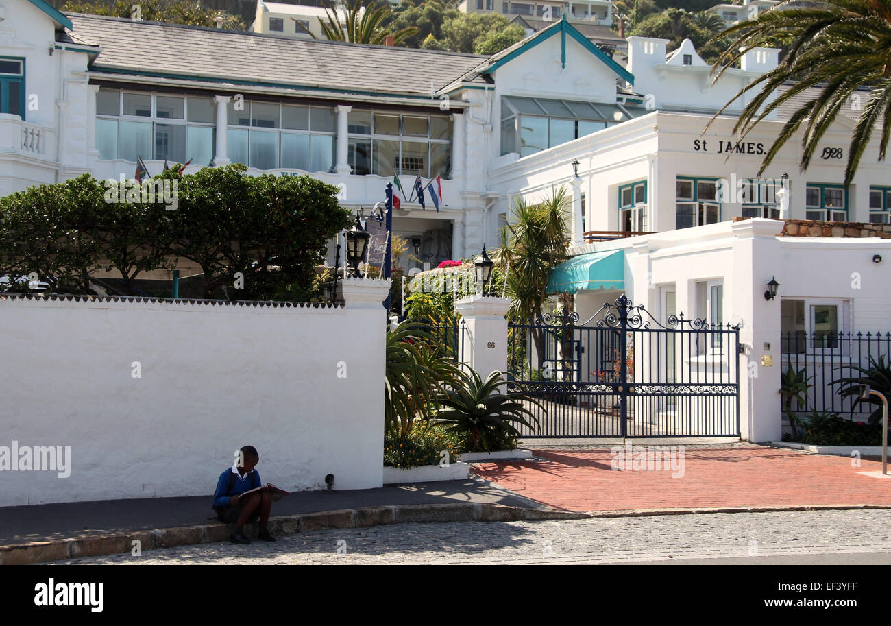 Lire un livre et de l'enfant assis dans la rue à St James, qui est une banlieue côtière exclusive de Cape Town Banque D'Images