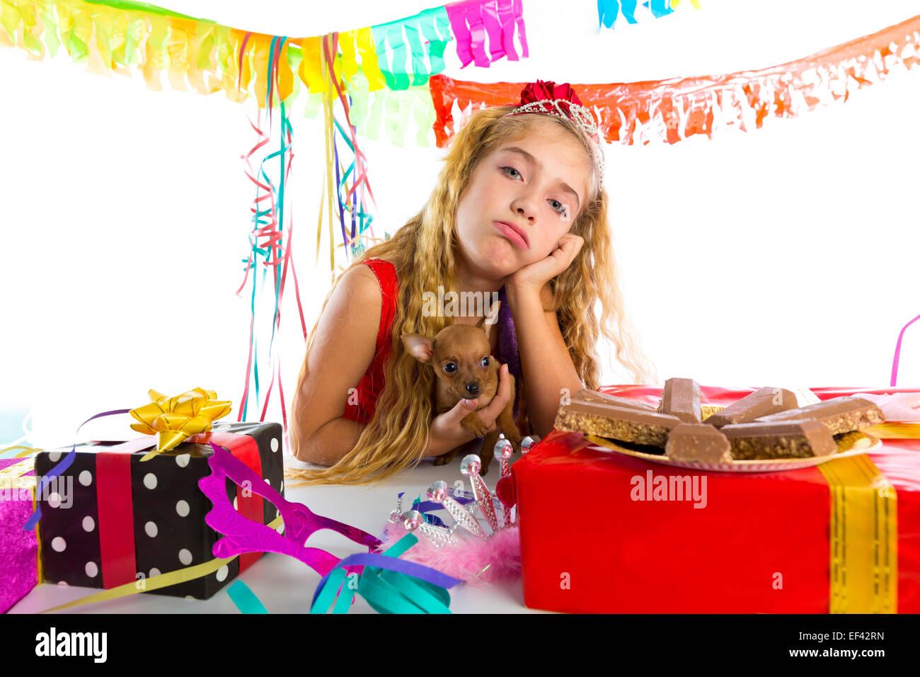 Geste ennuyé kid girl blonde en partie avec des chocolats et chiot chihuahua dog Banque D'Images