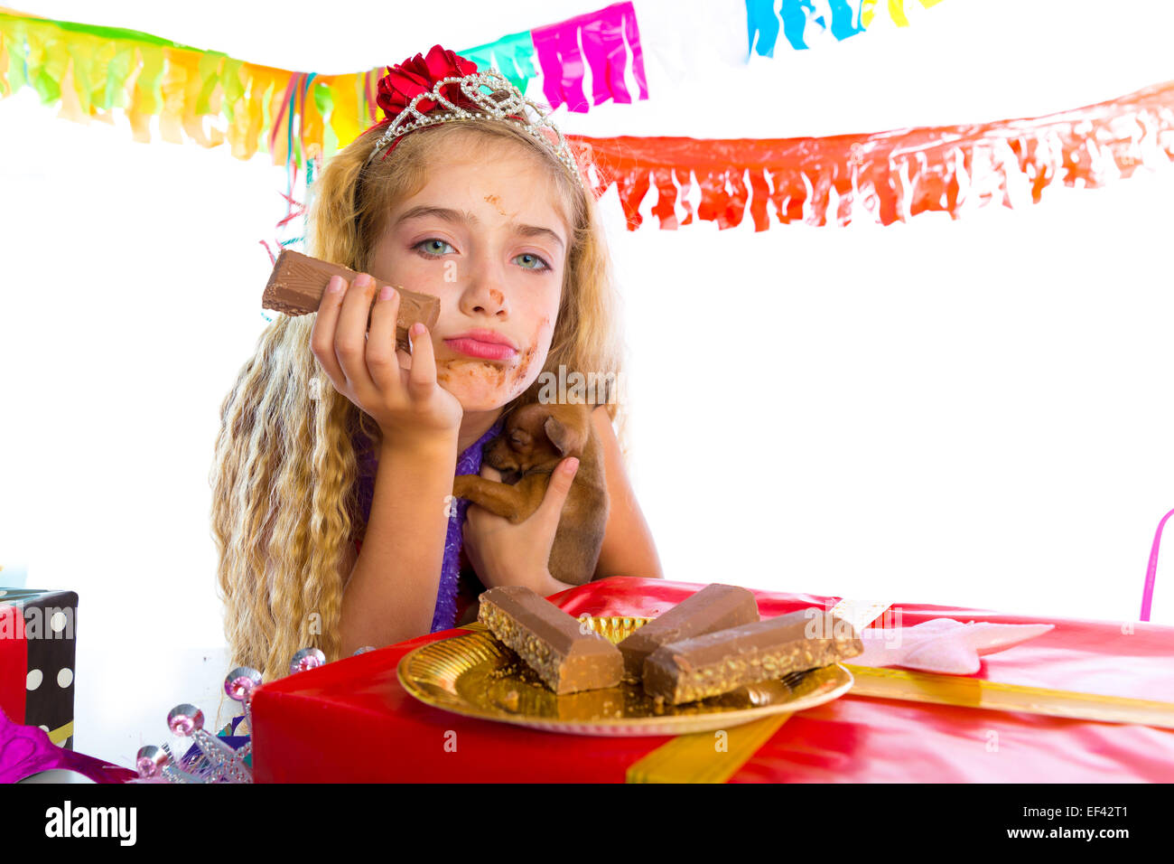 Geste ennuyé kid girl blonde en partie avec des chocolats et chiot chihuahua dog Banque D'Images
