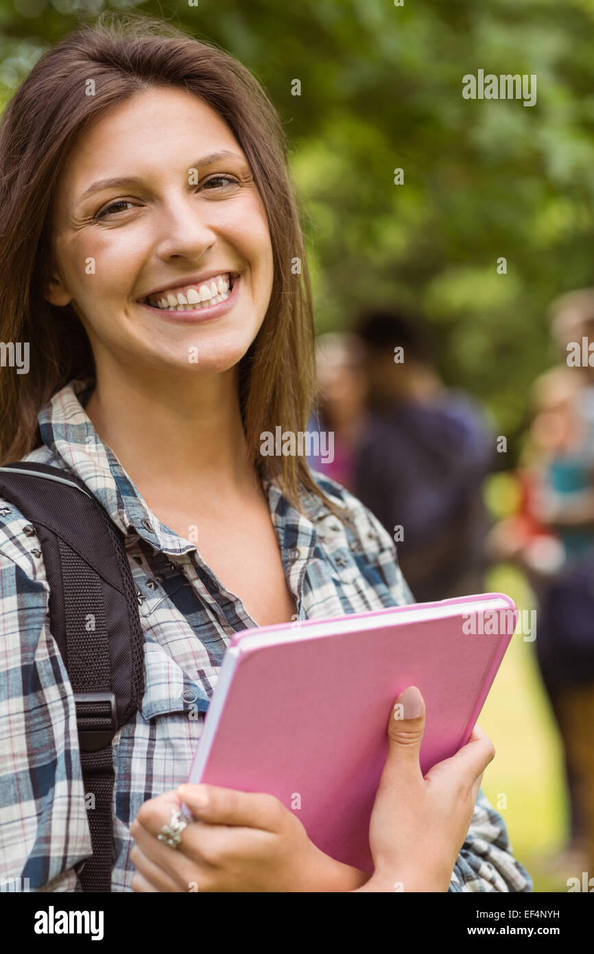 Portrait of a smiling student avec un sac à bandoulière et holding book Banque D'Images