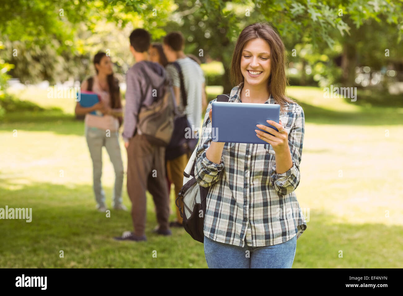 Smiling student avec un sac à bandoulière et using tablet computer Banque D'Images
