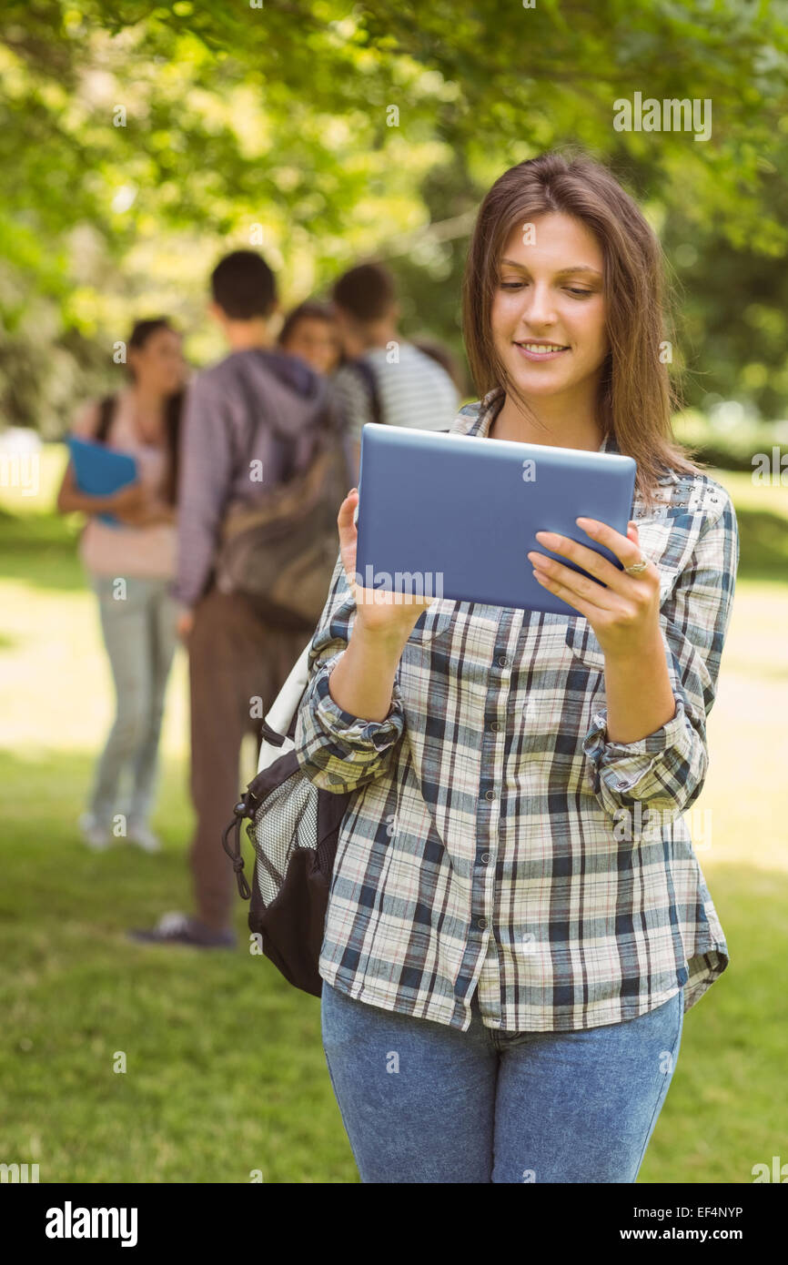 Smiling student avec un sac à bandoulière et using tablet computer Banque D'Images