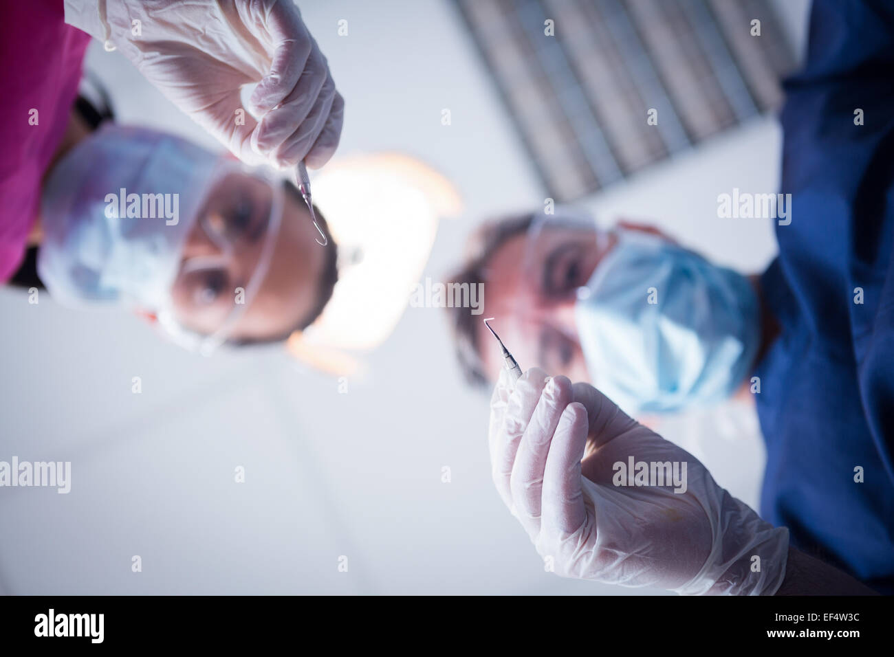 Dentiste et l'assistant se penche au patient avec des outils Banque D'Images