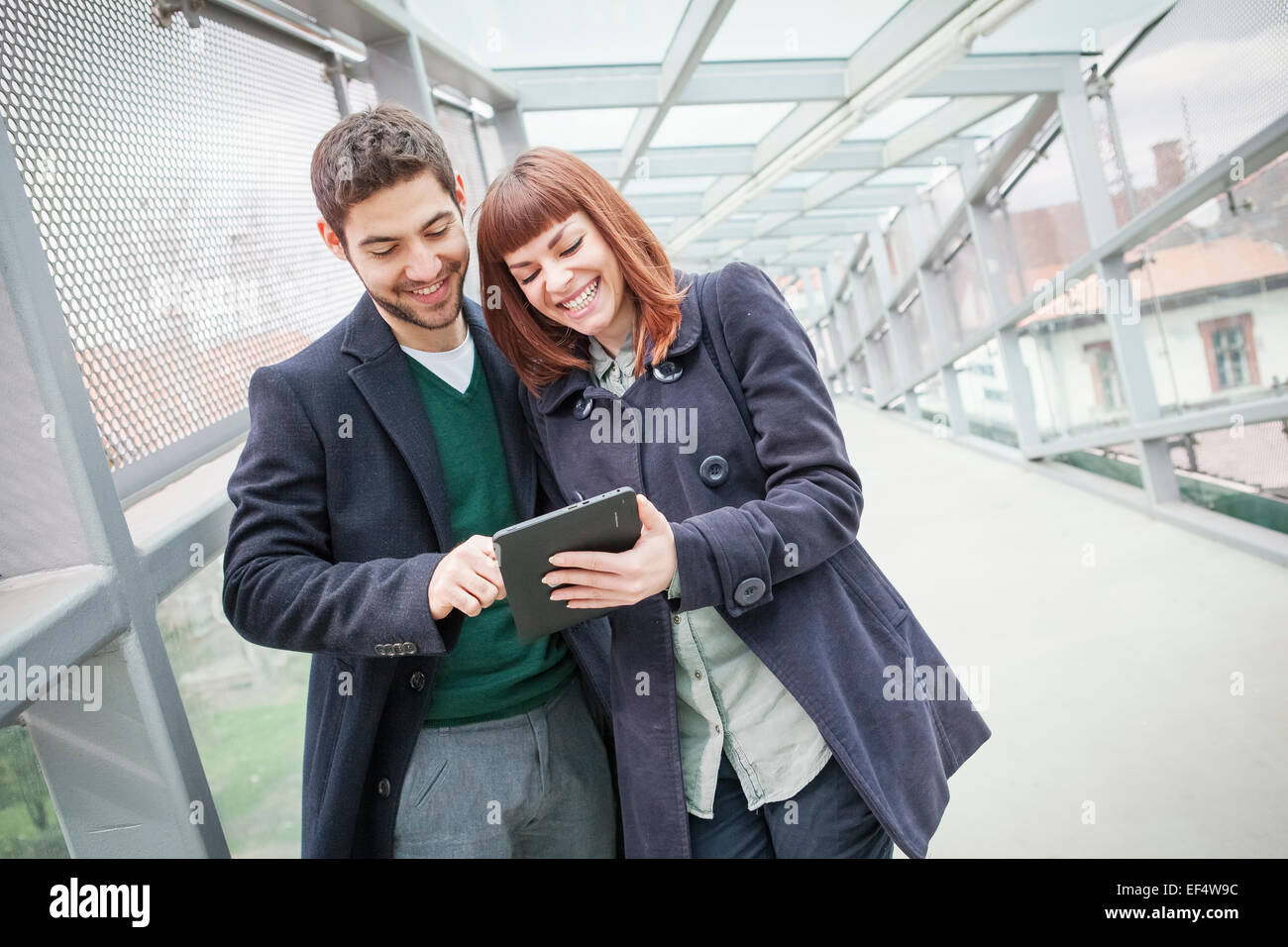 Jeune couple en bâtiment de l'aéroport using digital tablet Banque D'Images