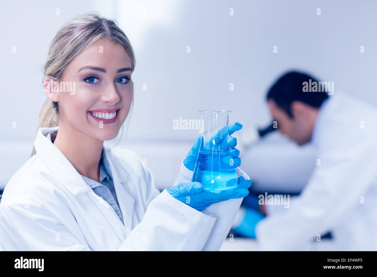 Étudiant en sciences chimiques holding blue in beaker Banque D'Images