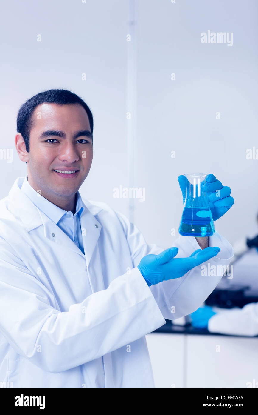 Étudiant en sciences chimiques holding blue in beaker Banque D'Images