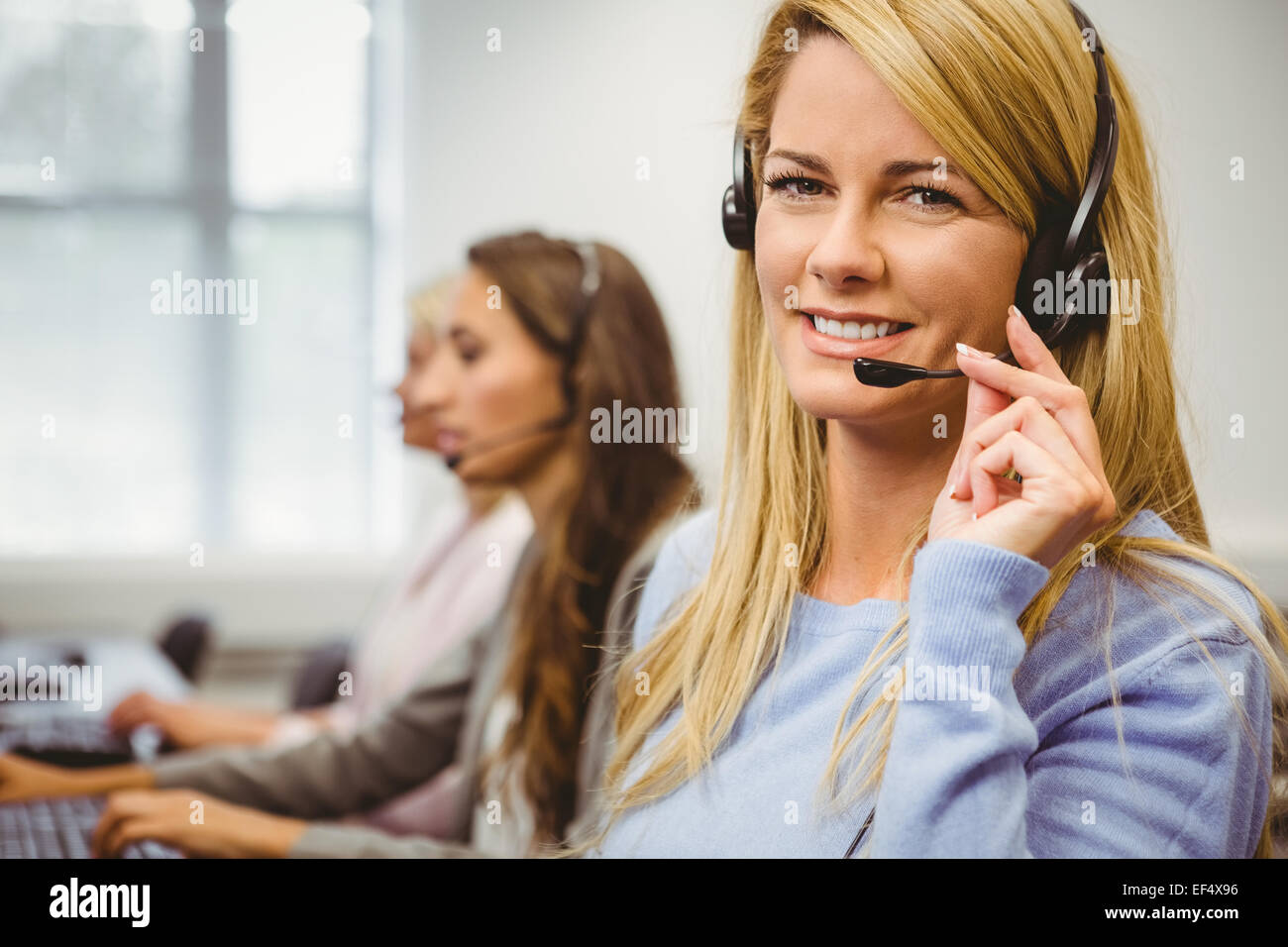 Smiling call centre agent en conversation sur le casque Banque D'Images