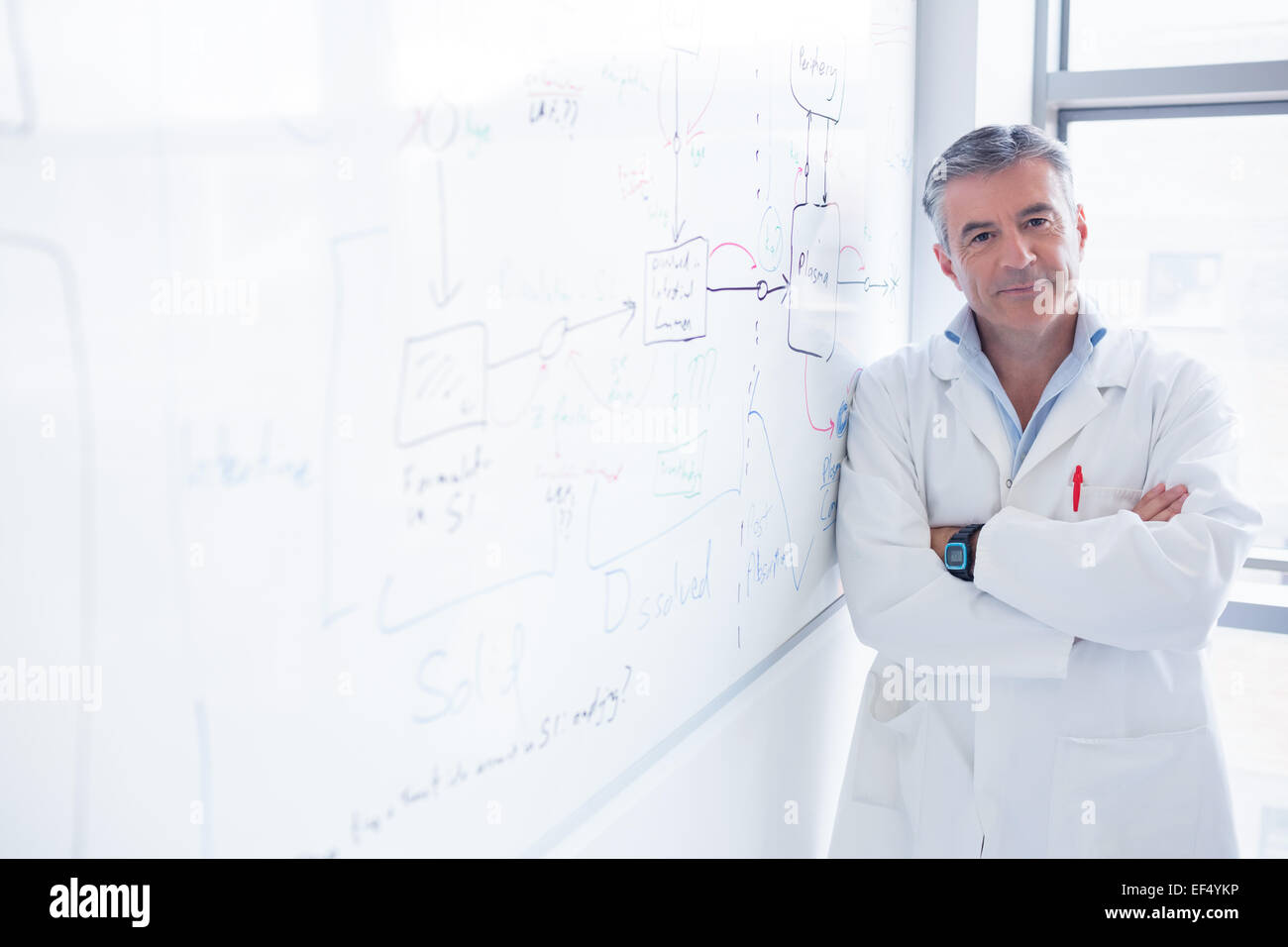 Smiling scientist appuyé contre le tableau blanc Banque D'Images